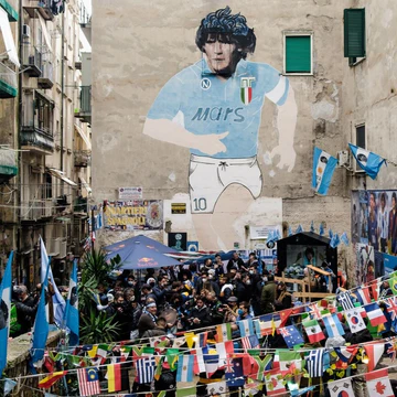 Maradona mural in Naples' Spanish Quarters with fans and tributes on the street
