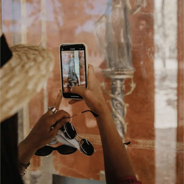 Tourist photographing ancient artwork on a phone in Italy, part of inStazione cultural tours.