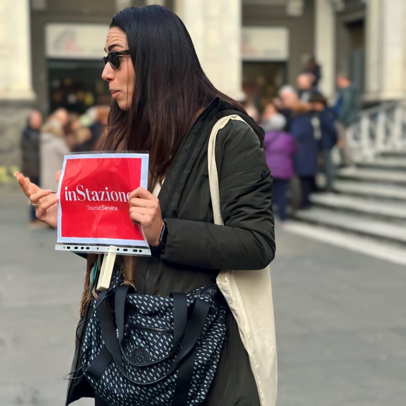 Instazione tour guide holding a Cappella Sansevero ticket sign in Piazza San Domenico Maggiore, Naples