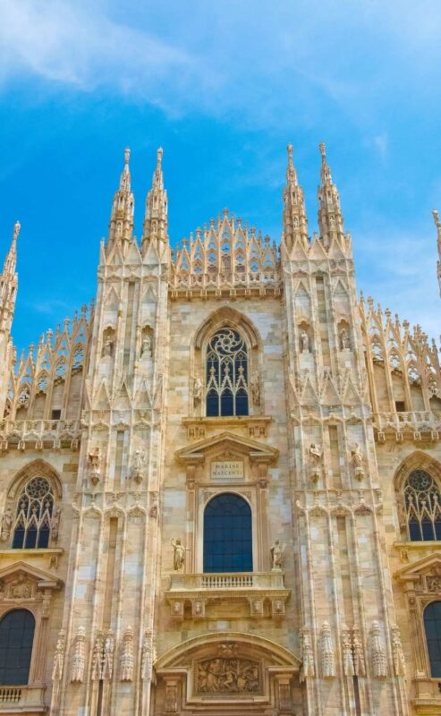 Detailed Gothic façade of the Duomo di Milano under clear blue sky