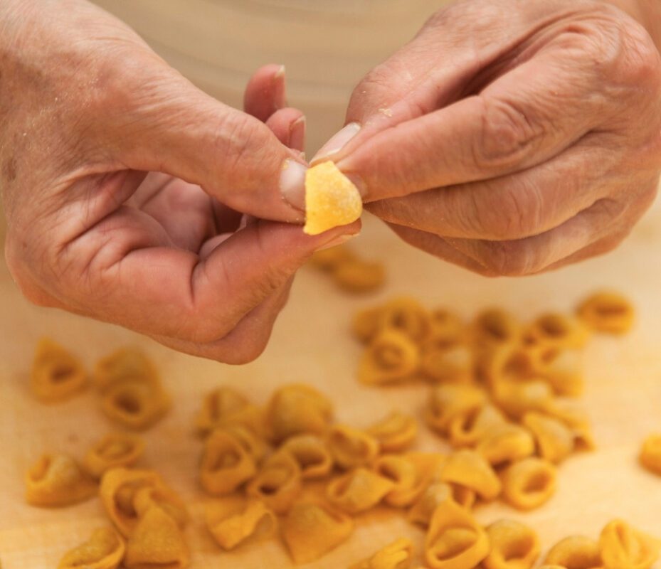 Close-up of hands making fresh tortellini, a symbol of traditional Bologna Street Food