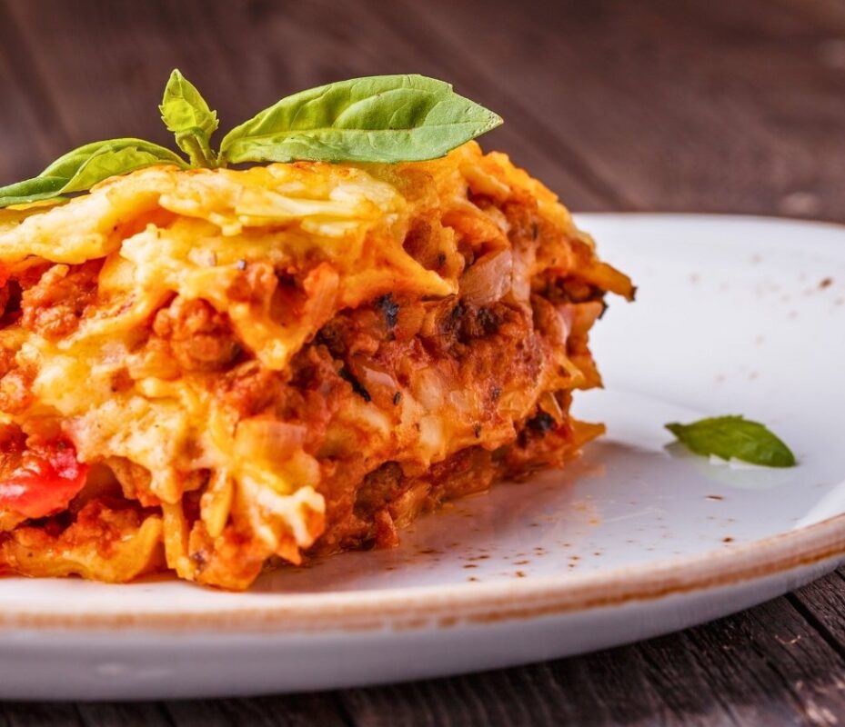 Baked lasagna alla bolognese served with fresh basil, a classic Bologna comfort food