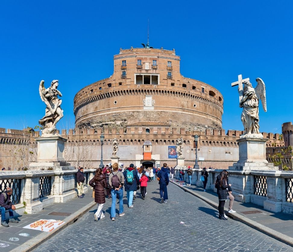 Tourists walking across Ponte Sant’Angelo toward Castel Sant’Angelo during a guided tour in Rome