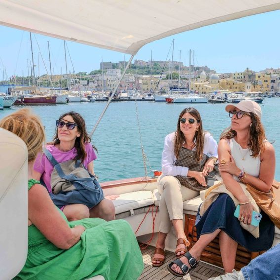 Travelers relaxing during Procida boat tour from Naples under sunny skies